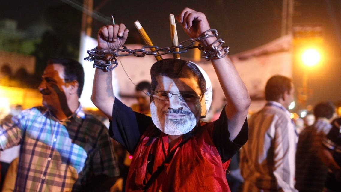 An anti-Mursi protester wears a mask depicting deposed president Mohamed Mursi, and chains on his hands, close to the presidential palace in Cairo July 19, 2013.