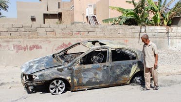 A man looks at a damaged vehicle after a bomb attack last night in Baghdad, July 28, 2013.