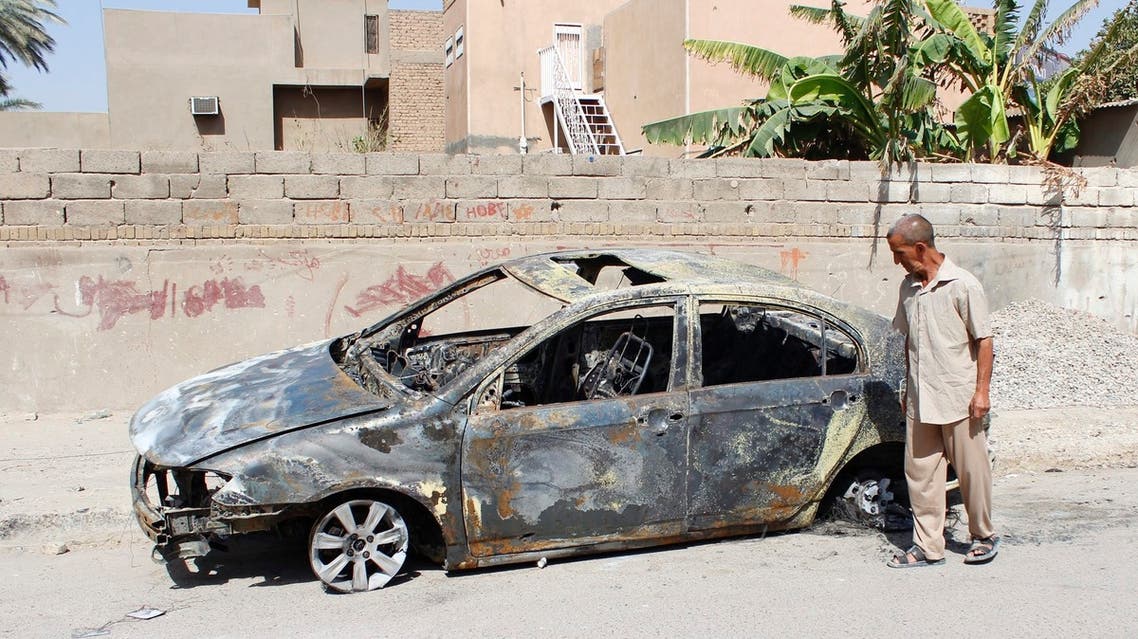 A man looks at a damaged vehicle after a bomb attack last night in Baghdad, July 28, 2013.