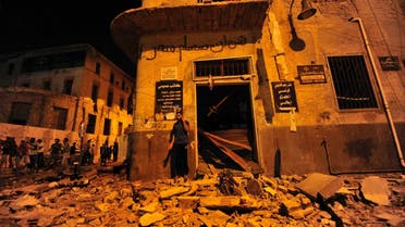 A man talks on his mobile phone while standing on debris after explosions at judicial buildings in Benghazi July 28, 2013.