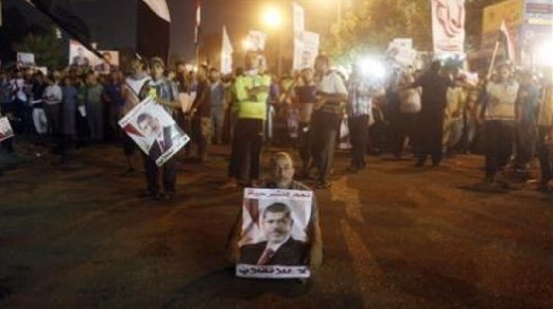 A supporter of deposed Egyptian President Mohammad Mursi, holding his poster, sits at a street during an anti-army rally that started from their sit-in area around Raba' al-Adawya mosque in Nasr City area in Cairo on July 30, 2013. (Reuters)