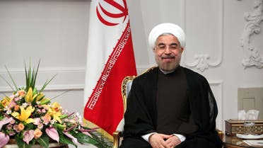 Iran's new President Hassan Rouhani sits next to the national flag on his first official day in office in Tehran on August 3, 2013. (AFP)