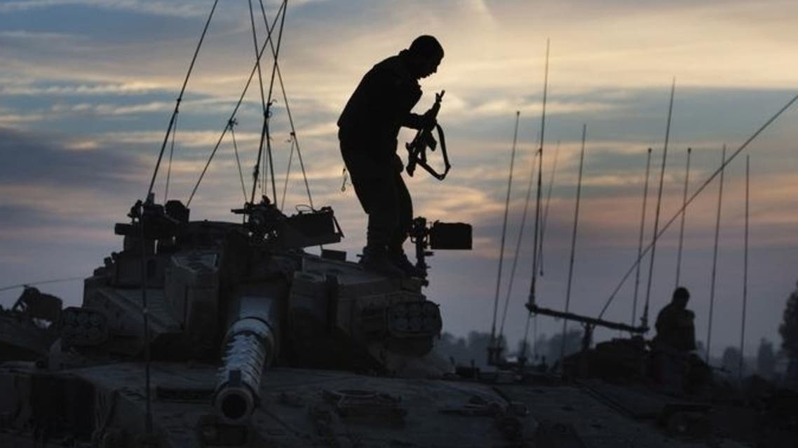 An Israeli soldiers stands on his tank at an army staging area on Nov. 21 near the Israel-Gaza Strip border.