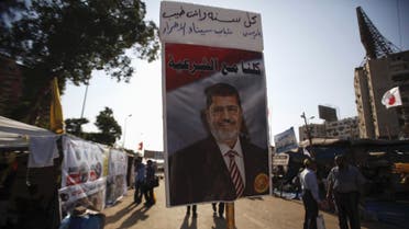 A poster of deposed Egyptian President Mohamed Mursi is seen as members of the Muslim Brotherhood and supporters of Mursi walk at the Rabaa Adawiya Square