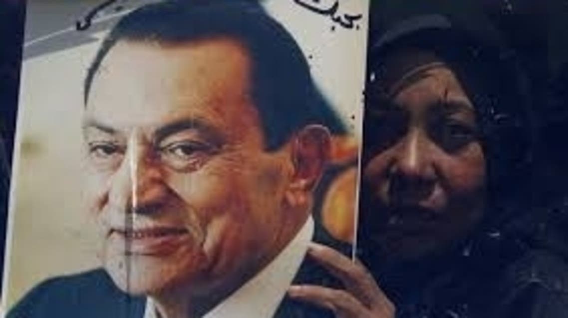 A supporter of Egypt's former president Hosni Mubarak holds a picture of him on a bus after Mubarak's trial, outside the police academy in Cairo April 13, 2013. reuters