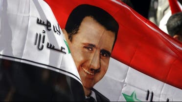 Syrians wave a flag with an image of President Bashar al-Assad during a rally in his support in Damascus. Photograph: Louai Beshara/AFP/Getty Images