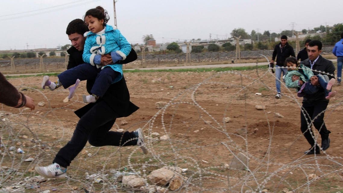 Syrians jump over barbed wire as they flee from the Syrian town of Ras al-Ain to the Turkish border town of Ceylanpinar, Sanliurfa province in this November 9, 2012 file photograph. (Reuters)