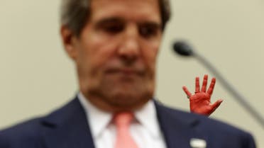 A protester holds up her hand, which is covered in red paint, as U.S. Secretary of State John Kerry testifies during a hearing on Syria. (AFP)