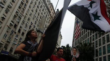 A protester raises the national flag of Syria during a demonstration against possible U.S. military intervention in Syria in front of the U.S. embassy in Rio de Janeiro, September 4, 2013. (Reuters)