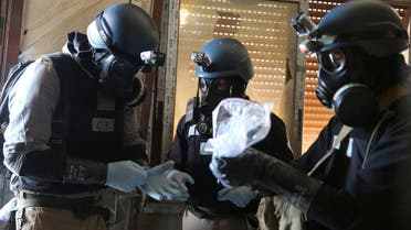 A U.N. chemical weapons expert, wearing a gas mask, holds a plastic bag containing samples from one of the sites of an alleged chemical weapons attack in the Ain Tarma neighbourhood of Damascus August 29, 2013. reuters