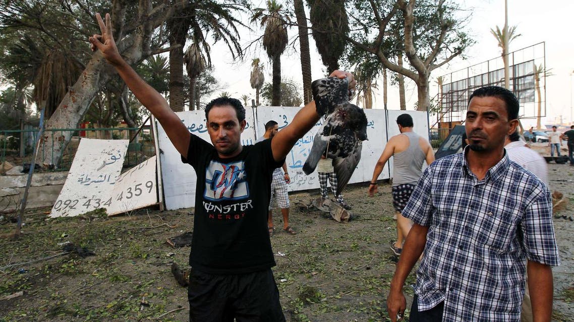 Libyan man shows a dead bird flashing the sign of victory outside a foreign ministry building that was damaged by a powerful blast on September 11, 2013 in the eastern Libyan city of Benghazi. afp