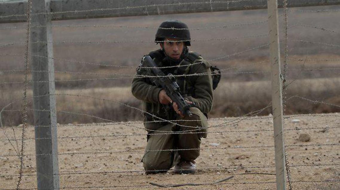 An Israeli soldier keeps watch as Palestinian youths demonstrate next to the security fence standing on the Gaza border with Israel, east of Khan Yunis, in the southern Gaza Strip. (File photo: AFP)