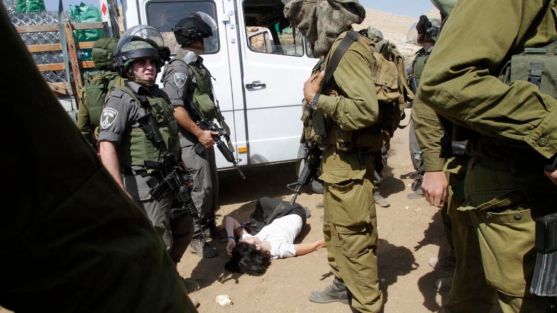 French diplomat Marion Castaing lays on the ground after Israeli soldiers carried her out of her truck containing emergency aid, in the West Bank herding community of Khirbet al-Makhul, in the Jordan Valley September 20, 2013. reu