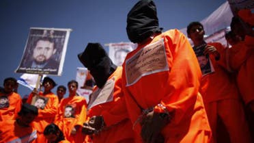 Former Guantanamo Bay detainees Walid al-Qadasi (R) and Sadiq Muhammad Saeed wear black hoods during a protest to demand the release of Yemeni detainees from Guantanamo Bay, outside the U.S. embassy in Sanaa April 16, 2013. reu