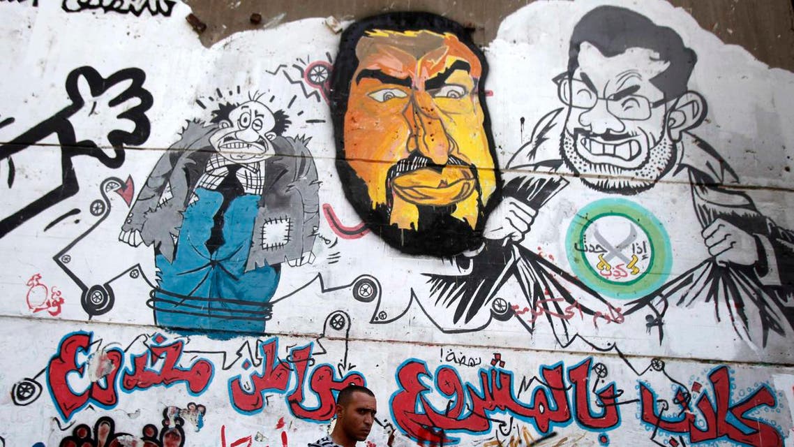 A man walks past graffiti depicting ousted Egyptian President Mohamed Mursi (R) and the Deputy Guide of the Muslim Brotherhood Khairat Al-Shater in downtown Cairo, September 24, 2013. (Reuters)