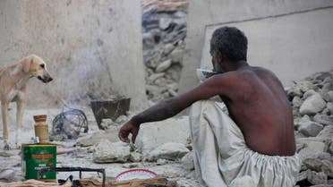 A survivor of an earthquake sits as he takes tea on the rubble of a mud house after it collapsed following the quake in the town of Awaran, southwestern Pakistani province of Baluchistan, September 25, 2013. reu