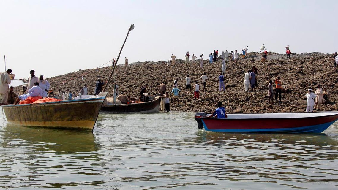 People use boats as they visit an island that rose from the sea following an earthquake, off Pakistan's Gwadar coastline in the Arabian Sea September 25, 2013. reu