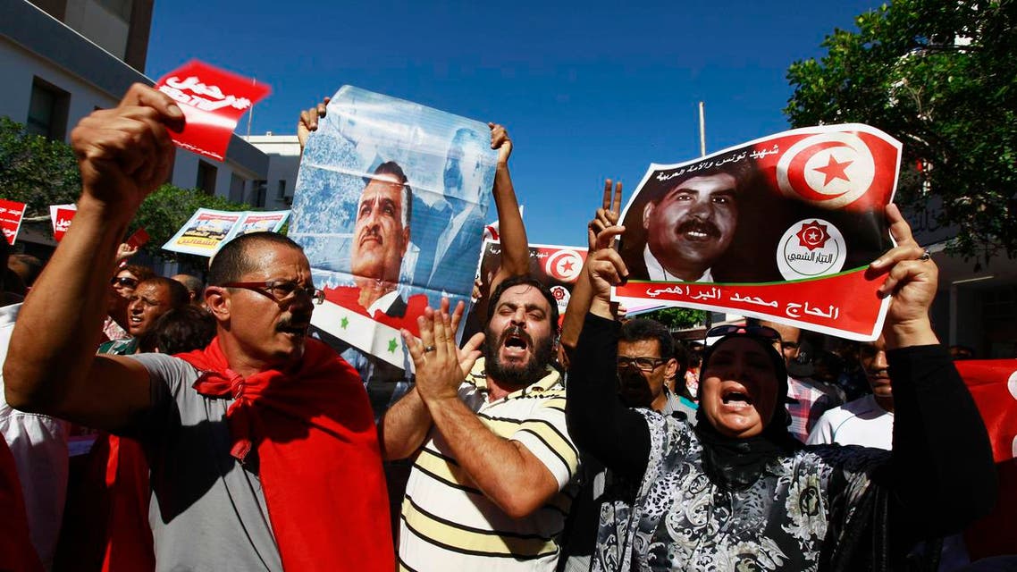 Protesters hold up and a picture of slain opposition leader Mohamed Brahmi during an anti-government demonstration rallying for the dissolution of the Islamist-led government in Sfax, 170 miles (270 km) southeast of Tunis September 26, 2013.