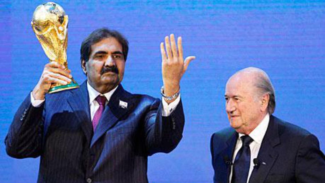 Qatar's Sheikh Hamad bin Khalifa al-Thani, left, holds up the World Cup trophy after his country's bid was controversially awarded the 2022 tournament by Fifa. Photograph: Christian Hartmann/Reuters