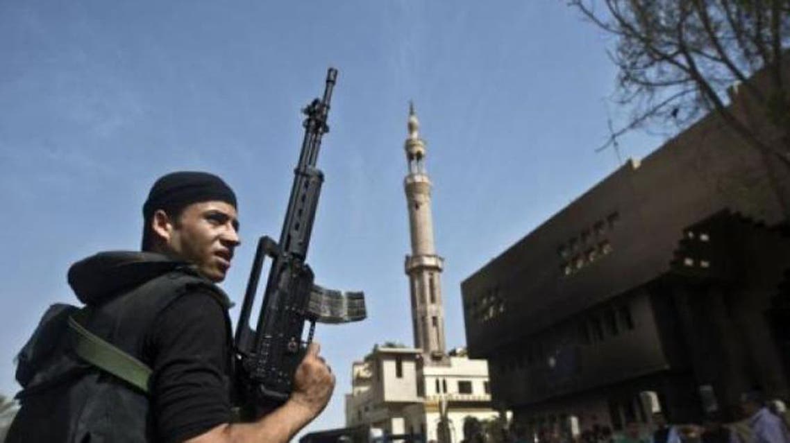 An Egyptian armed policeman stands in front of a burnt police station in the village of Kerdassah on the outskirts of Cairo, on September 19, 2013. (File photo: AFP)