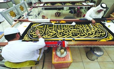Saudi worker sew Islamic calligraphy in gold thread on a drape to cover the Kaaba at the Kiswa factory in the holy city of Mecca afp