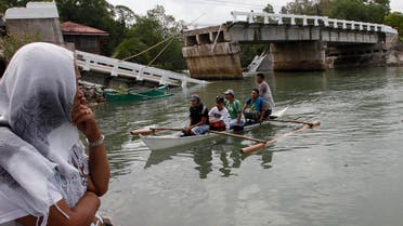 Villagers ride on a boat to cross a river after bridge was damaged in Loon, Bohol, October 16, 2013, a day after an earthquake hit central Philippines. 