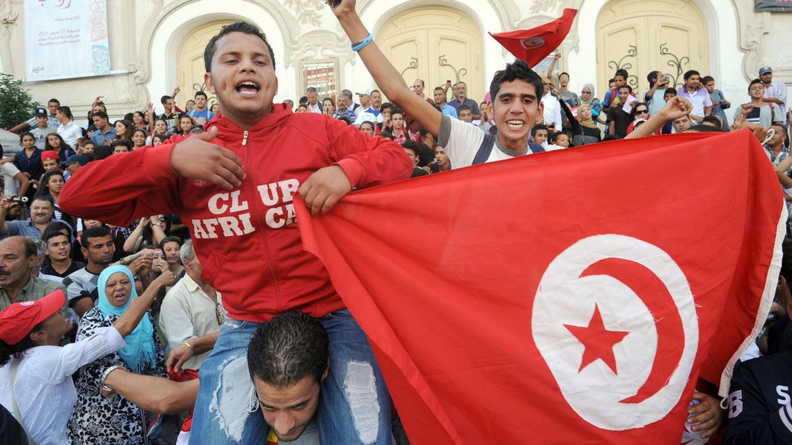 Tunisian young protesters hold a national flag shouting slogans during a demonstration in Tunis' central Habib Bourguiba Avenue on October 23, 2013 demanding the resignation of Tunisia's Islamist-led government, ahead of a national dialogue aimed at ending months of political deadlock.