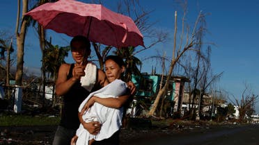 A couple carrying their sick child walk to a Philippine Red Cross service center in Tacloban Nov. 15, 2013. The death toll from a powerful typhoon doubled overnight in one Philippine city alone, reaching 4,000. (Reuters)