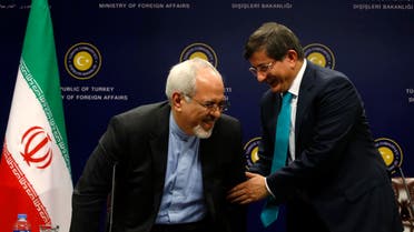 Turkish Foreign Minister Ahmet Davutoglu (R) helps Iranian Foreign Minister Mohammad Javad Zarif to stand during a news conference in Ankara Nov. 1, 2013. (Reuters)