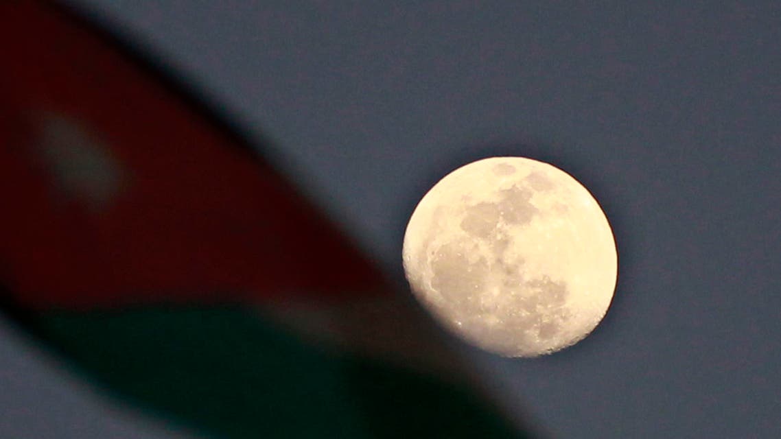 A Jordanian National flag is pictured next to the moon during an anti-government rally organized by protesters known as "Youth of March 24 Movement" to demand for more freedom and access to corruption cases in Amman March 24, 2013.