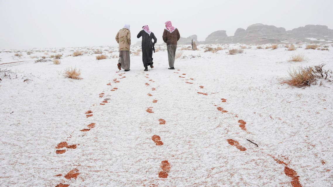 Saudi men walk as their footprints are seen after a snowstorm in Alkan village, west of Saudi Arabia December 13, 2013.