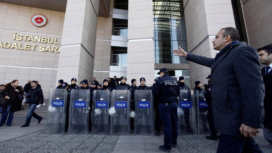 A plainclothes police officer reacts as riot police stand guard in front of the courthouse in Istanbul, Dec. 20, 2013. (Reuters)