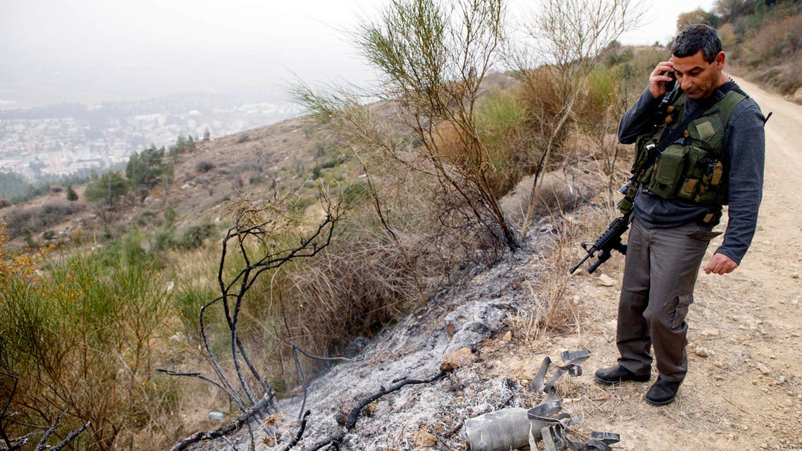 An Israeli security coordinator stands next to the remains of a rocket after it landed near the northern town of Kiryat Shmona December 29, 2013.