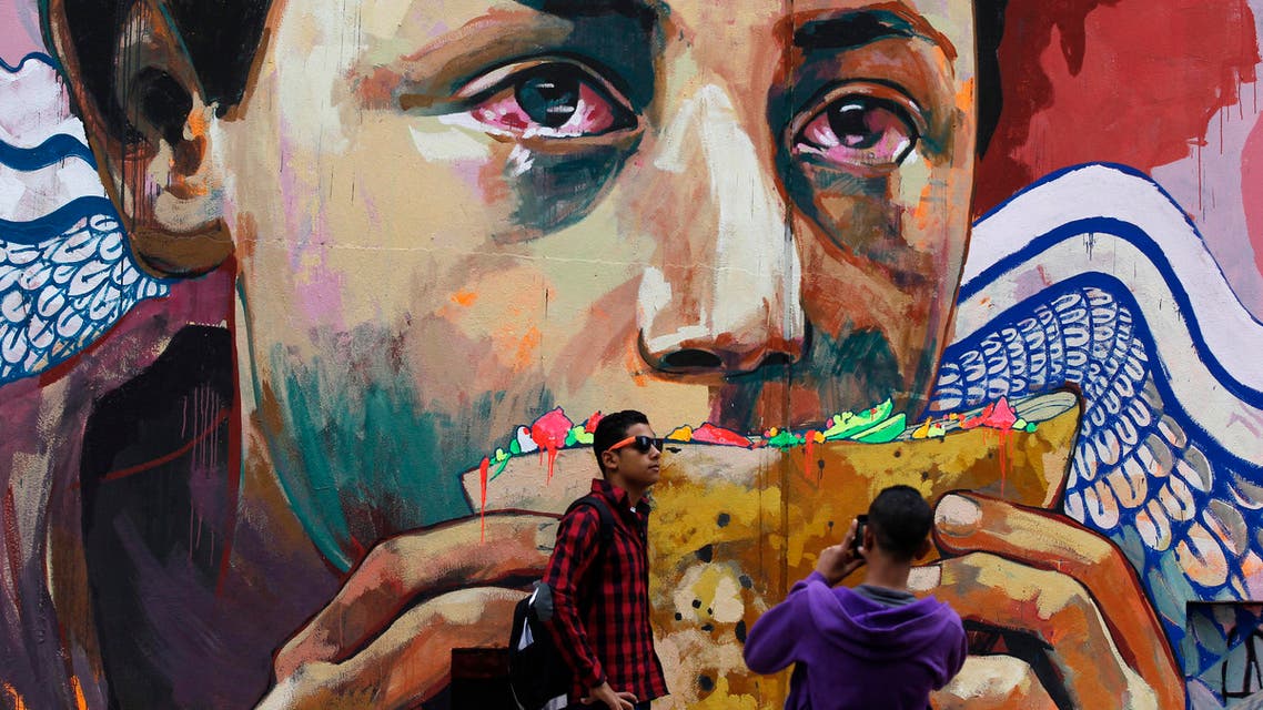 Youths take photos in front of graffiti depicting poverty and homelessness in downtown Cairo December 5, 2013. (Reuters)