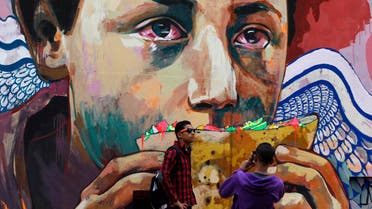 Youths take photos in front of graffiti depicting poverty and homelessness in downtown Cairo December 5, 2013. (Reuters) 