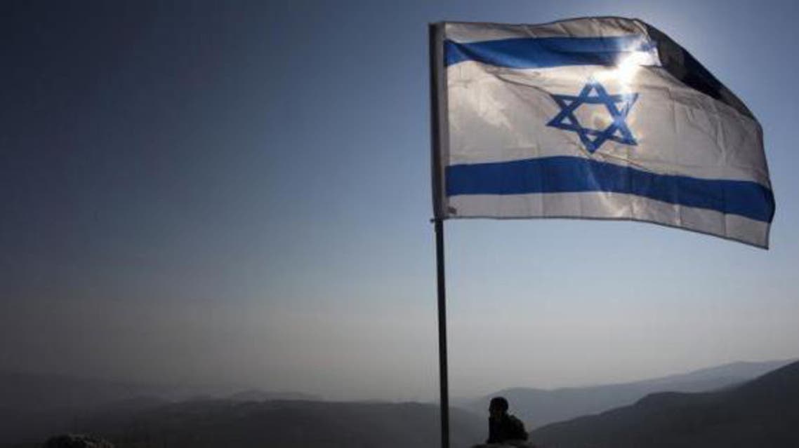 An Israeli soldier stands guard under an Israeli national flag during a tour made by Israeli parliament members in the Jordan Valley near the Jewish settlement of Maale Efrayim January 2, 2014.