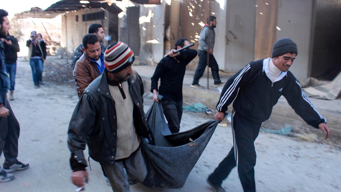 Men carry a body, believed to be one of the detainees held and executed by fighters from the Islamic State in Iraq and the Levant (ISIL). (Reuters)