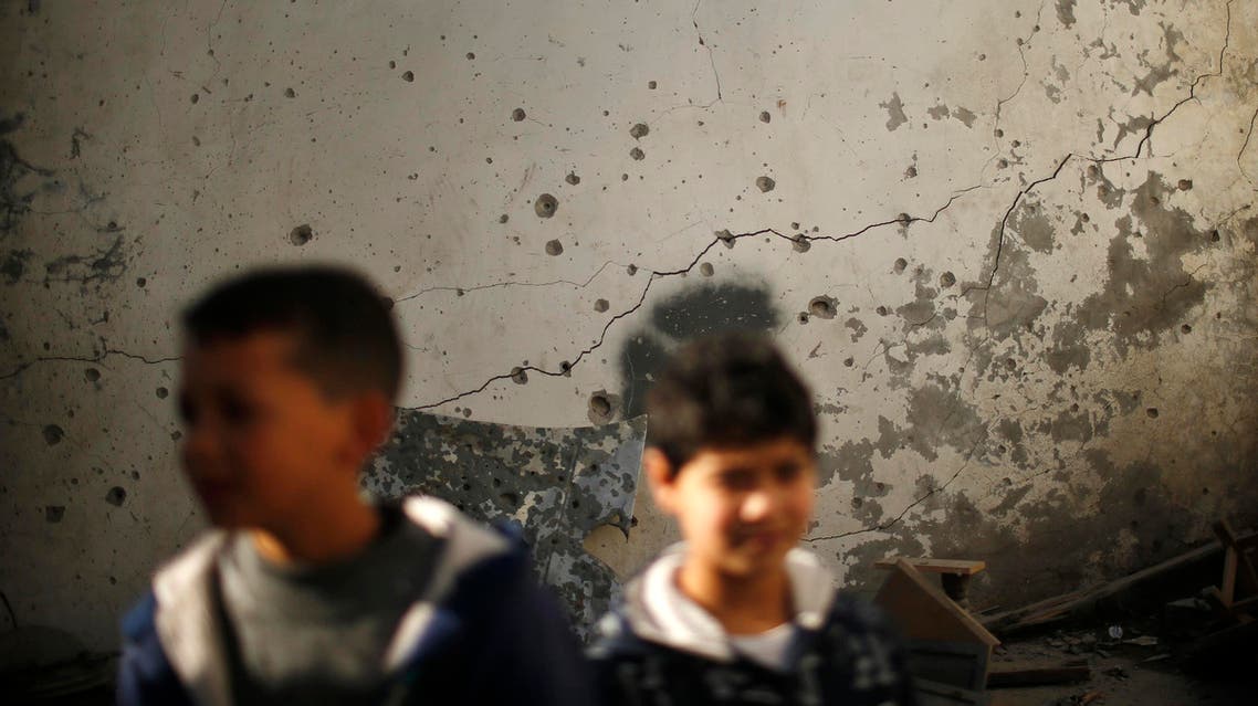 Boys stand in front of a damaged wall as they inspect a house yard which witnesses said was hit in an Israeli air strike, in Gaza City January 16, 2014