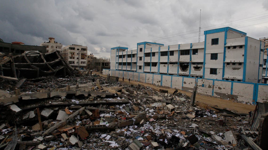 Palestinians walk past a destroyed building and a school, which witnesses said was damaged in an Israeli air strike, in Gaza City November 24, 2012.