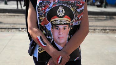 A supporter of Egypt's army chief General Abdel Fatah al-Sisi hugs his poster during celebrations of the third anniversary of Egypt's uprising, in front of El-Thadiya presidential palace in Cairo January 25, 2014. 