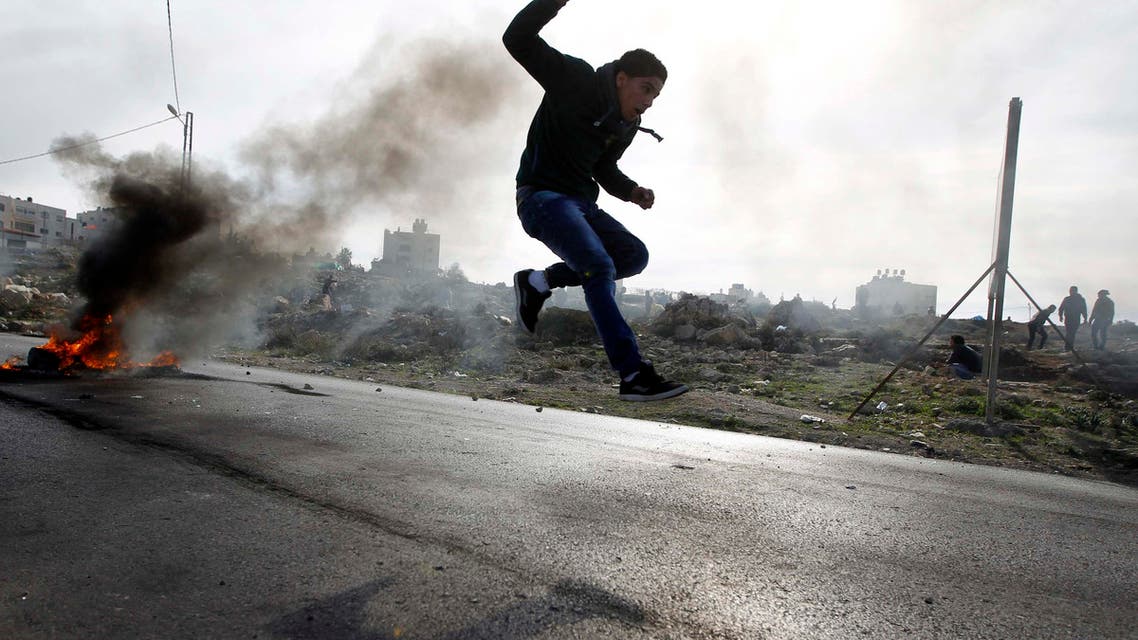 A Palestinian protester jumps as tyres burn in the background during clashes with Israeli soldiers in Jalazoun refugee camp near the West Bank city of Ramallah January 31, 2014.