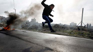 A Palestinian protester jumps as tyres burn in the background during clashes with Israeli soldiers in Jalazoun refugee camp near the West Bank city of Ramallah January 31, 2014. 