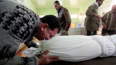 A man reacts near the shrouded body of his son, who was killed by a car bomb attack, before his burial at a cemetery in Najaf, 160 km (100 miles) south of Baghdad Jan. 31, 2014. (Reuters)