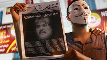 A demonstrator holds up a poster with an image of slain opposition figure Mohamed Brahimi to protest his assassination in Tunis, July 25, 2013. reuters