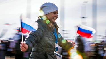 A girl wearing a fan entrance ticket runs with Russian national flags at the Olympic Park during the Sochi 2014 Winter Olympics Games February 9, 2014. 