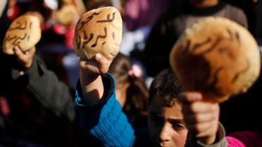 Palestinian children hold bread as they take part in a rally to show solidarity with Palestinian refugees in Syria's main refugee camp Yarmouk, in Gaza City January 16, 2014.  reuters