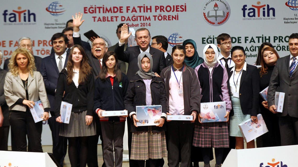 اردوغان أثناء تسليمه أجهزة كمبيوتر لوحية لعدد من طلاب المدارس