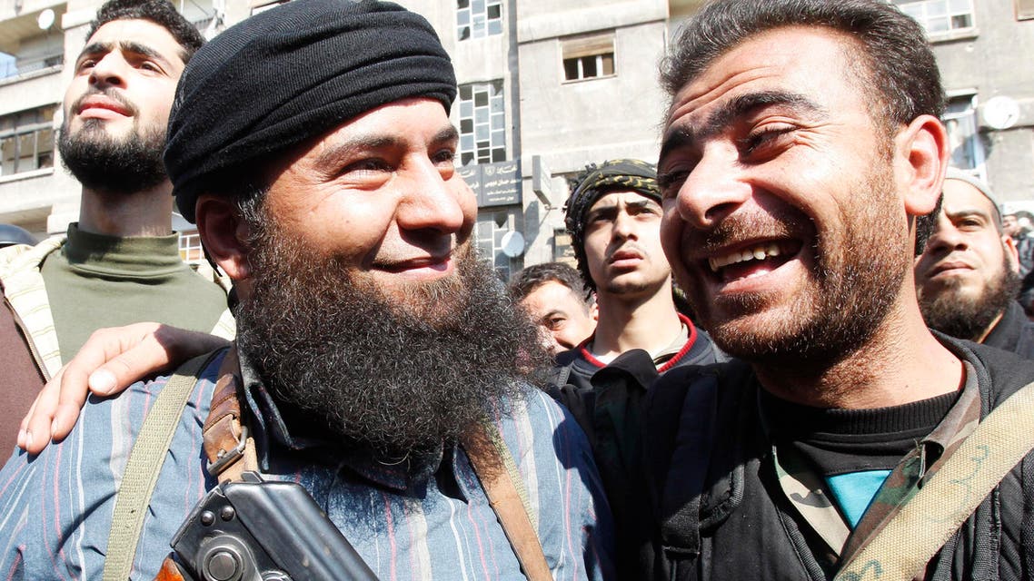 A soldier loyal to Syria's President Bashar al-Assad (R) jokes with a member of Syria's armed opposition forces in Babila town, southeast Damascus