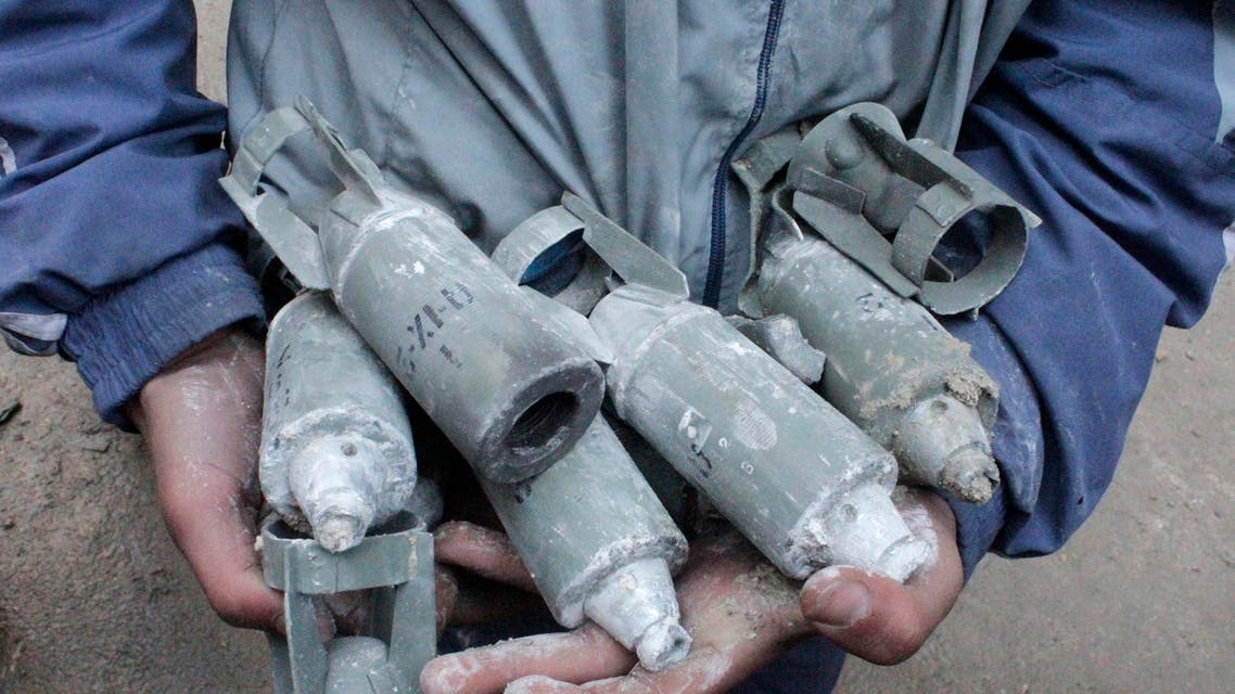 A boy holds unexploded cluster bombs after jet shelling by forces loyal to Syria's President Bashar al-Assad in the al-Meyasar district of Aleppo February 21, 2013. reuters