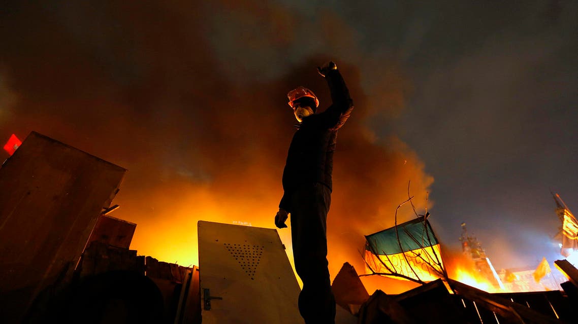 An anti-government protester rises his fist behind burning barricades in Kiev's Independence Square Feb. 19, 2014. (Reuters)